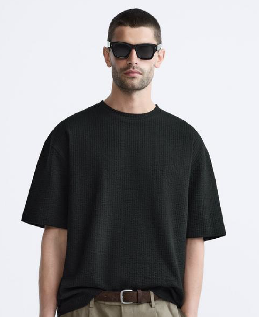 Model wearing a black bird embroidered t-shirt on a white studio background