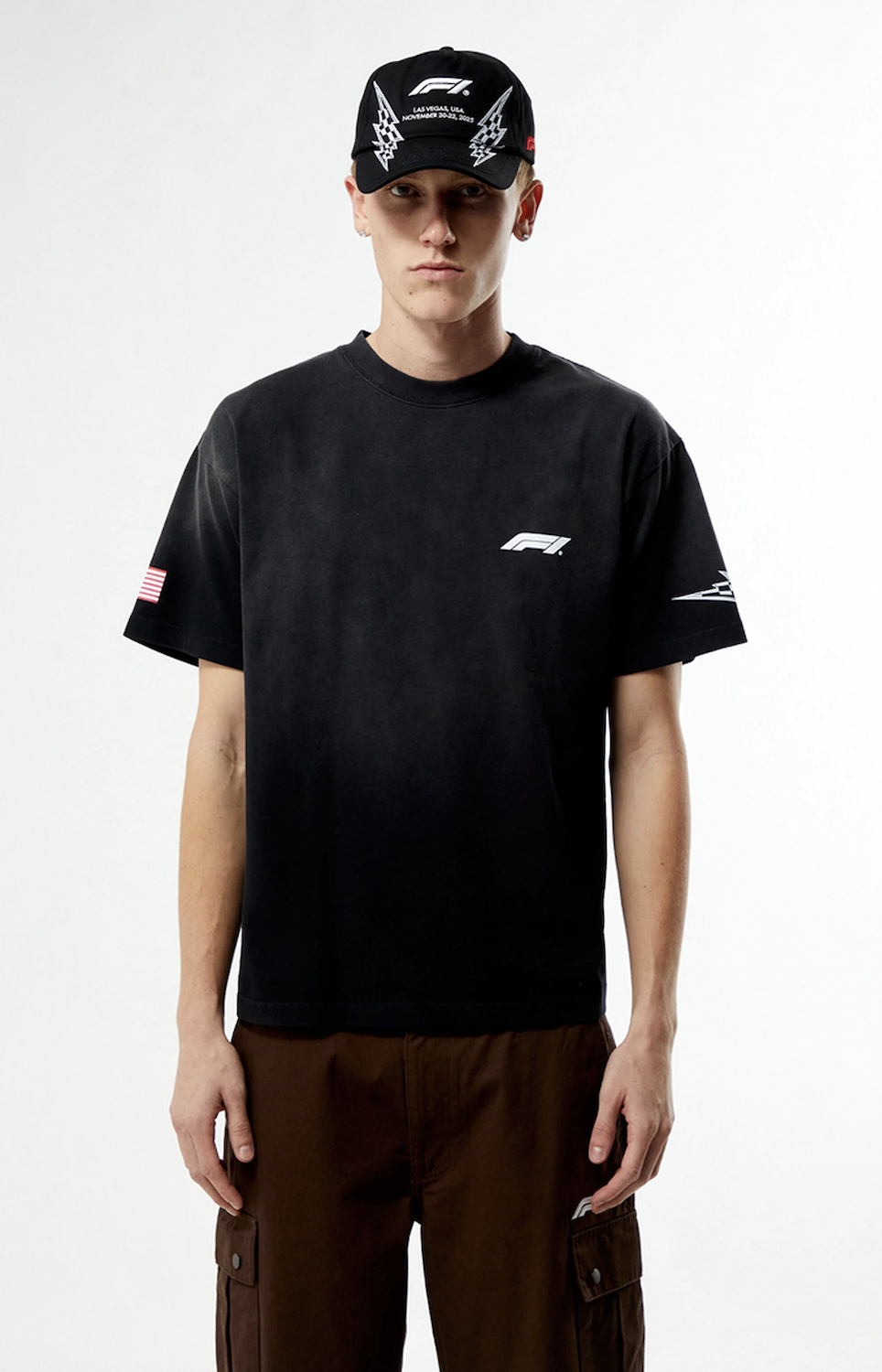 Model wearing a black F1 t-shirt and cap on a white studio background