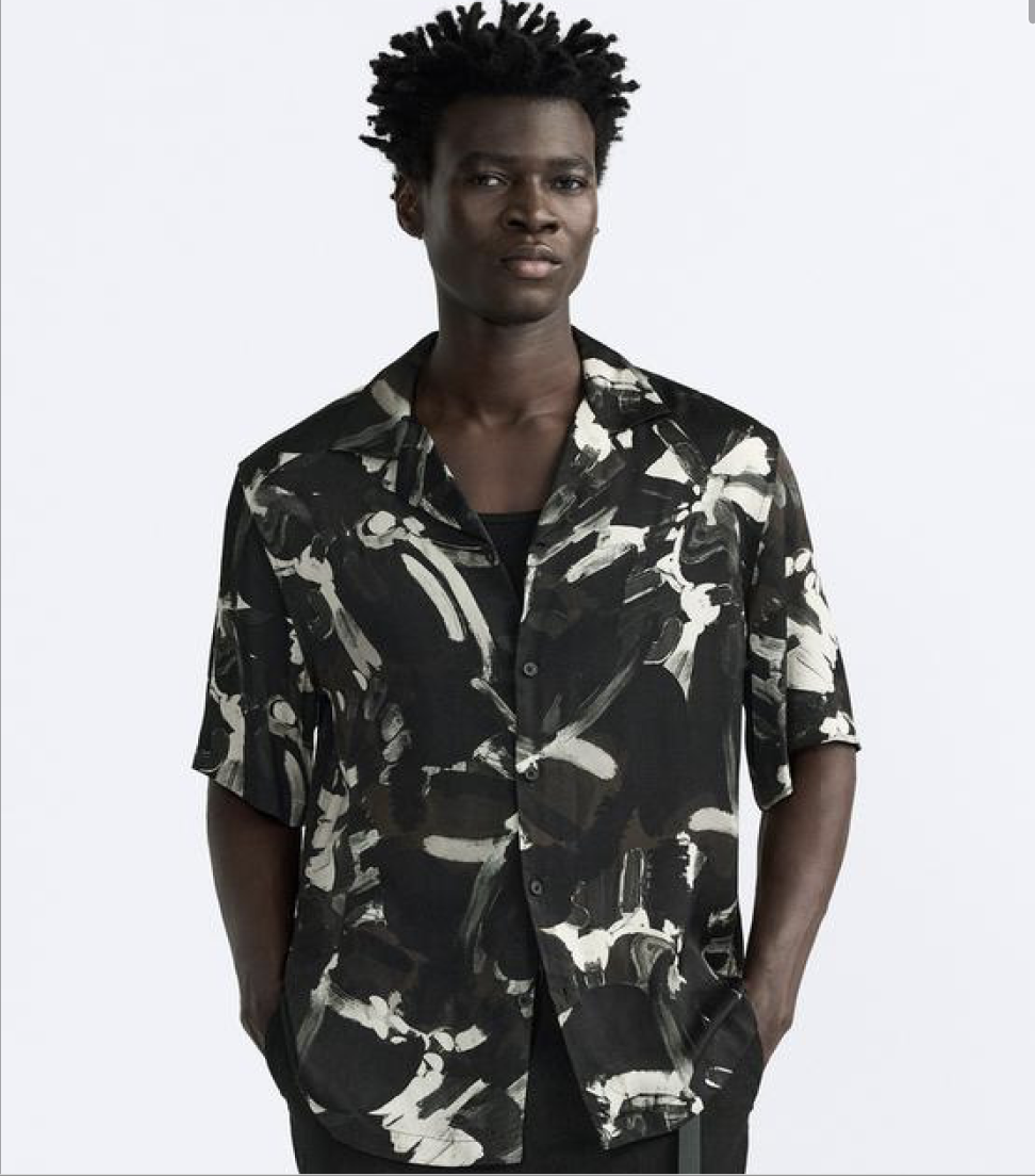 Model wearing a textured tee and amber sunglasses on a white studio background